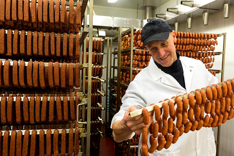 Josef's Artisan maker inspecting rows of hanging sausages in production