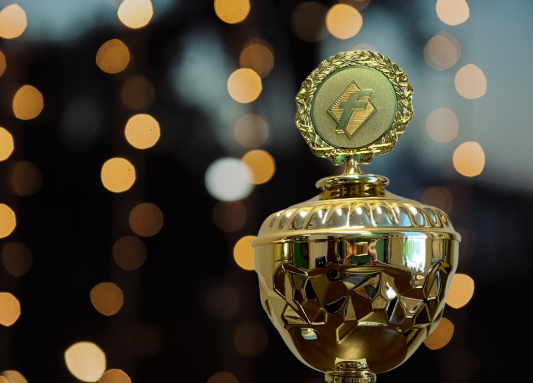 A gold award trophy against warm lights